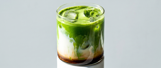 Dirty matcha latte in a clear glass — matcha green layer over milk with an espresso shot poured on top, served over ice