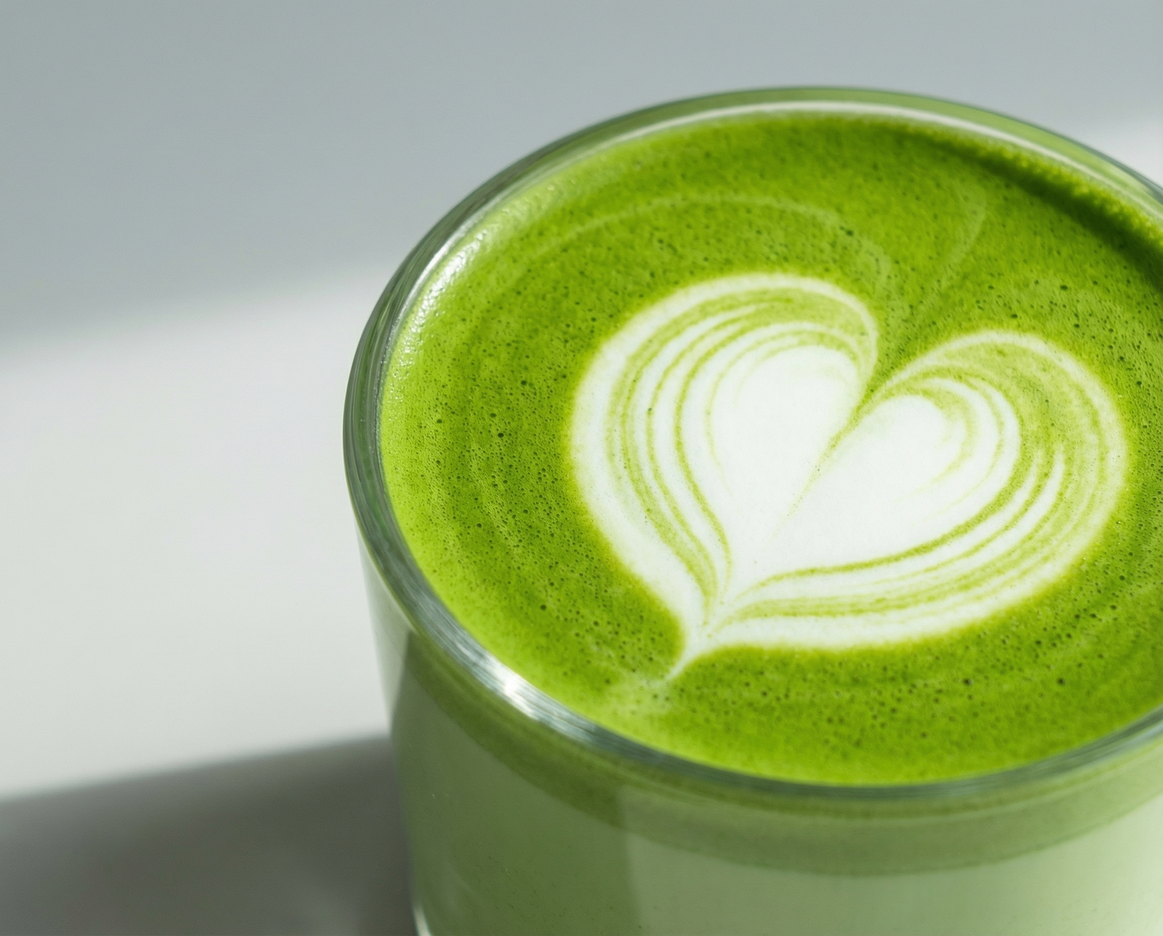 Close-up of vivid green matcha latte with a heart-shaped latte art